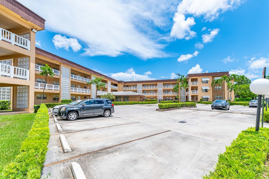 a parking lot with cars in front of an apartment building