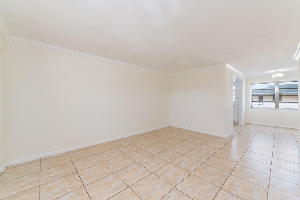 an empty living room with tile flooring and white walls