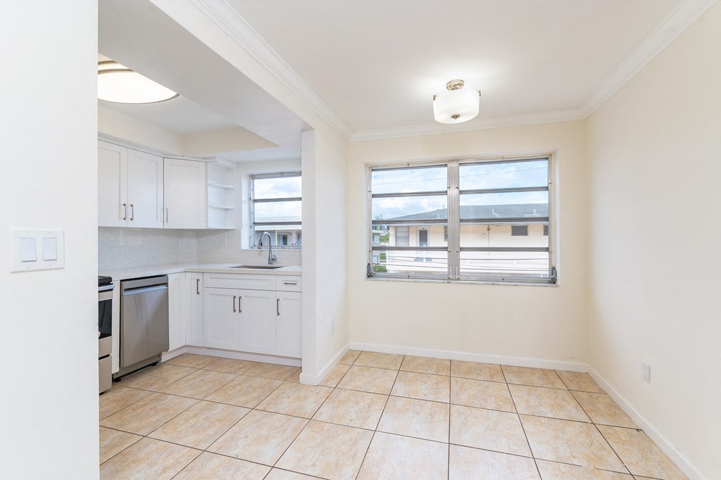 an empty kitchen with a window and a tiled floor