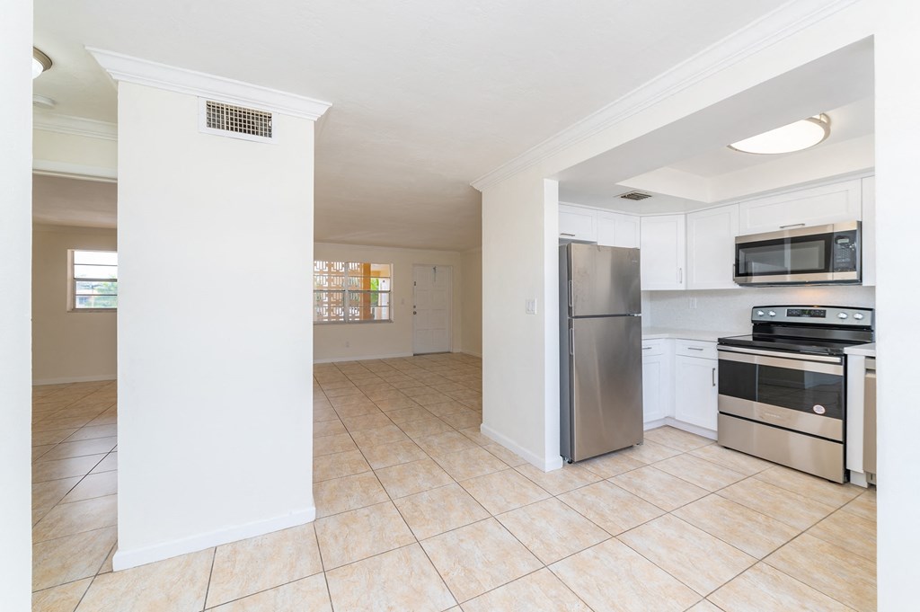 an empty kitchen with stainless steel appliances and white cabinets