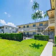 a mansion with a green lawn and palm trees