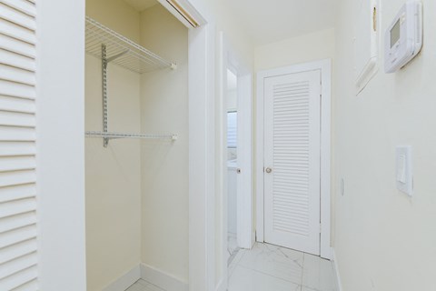 a room with a closet and a closet door and a door to a shower