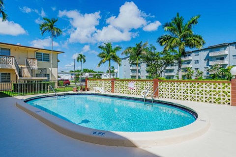 a swimming pool in front of a building with palm trees