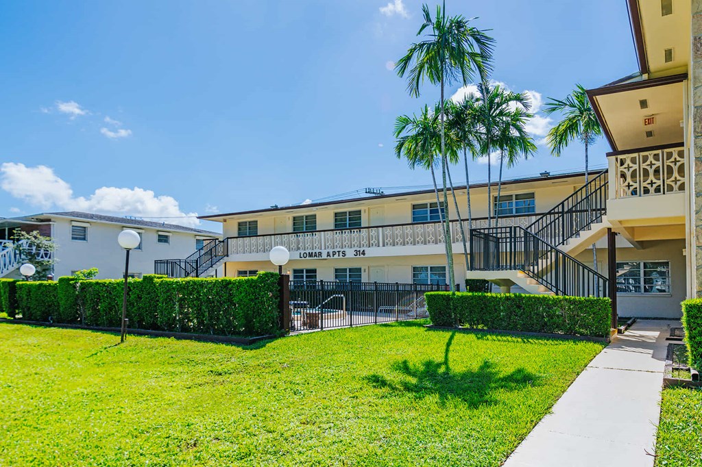 a building with a lawn and palm trees in front of it
