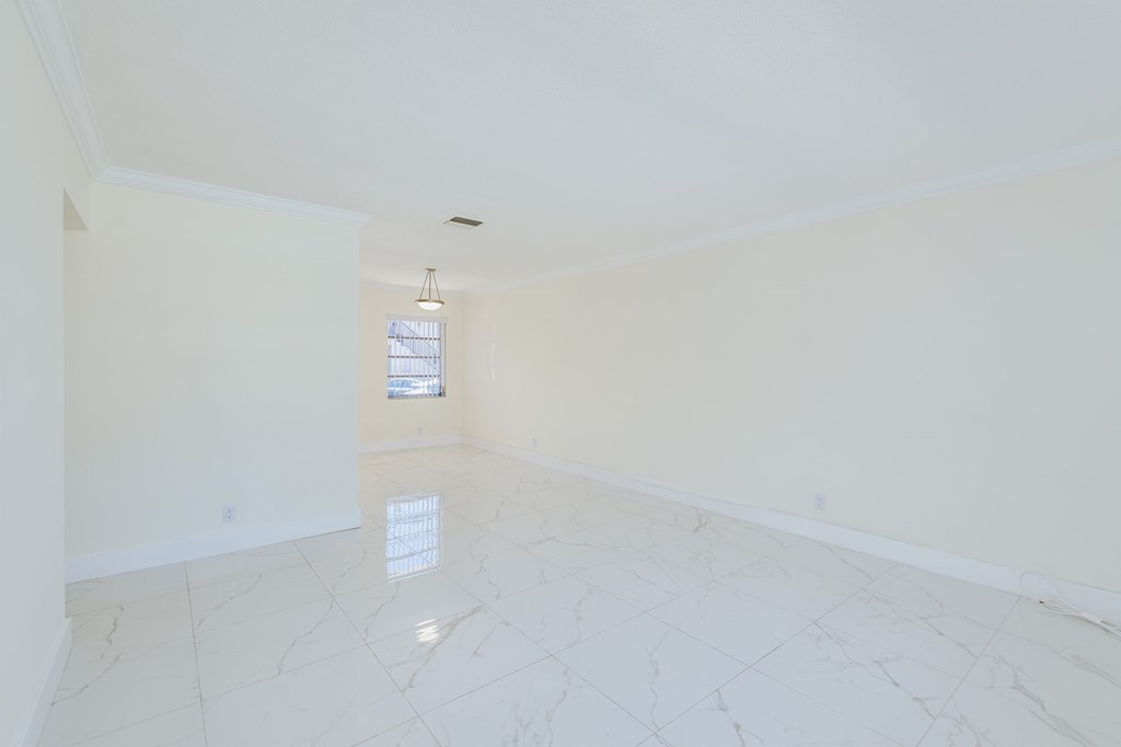 an empty living room with white marble floors and a window