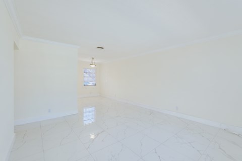 an empty living room with white marble floors and a window