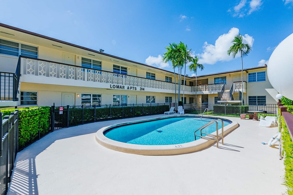a swimming pool in front of a building with palm trees