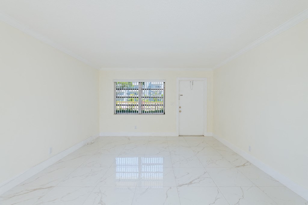 an empty room with a window and white marble floors