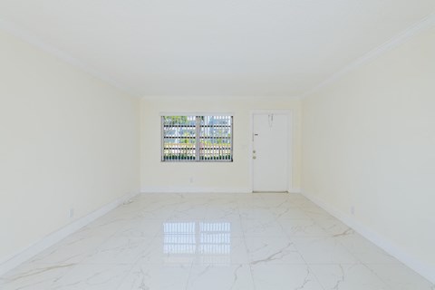 an empty room with a window and white marble floors