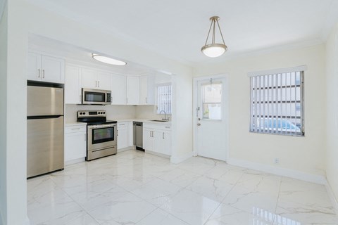 an empty kitchen with stainless steel appliances and white cabinets