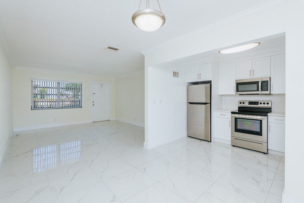 an empty kitchen with stainless steel appliances and white cabinets