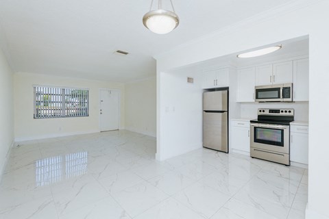 an empty kitchen with stainless steel appliances and white cabinets