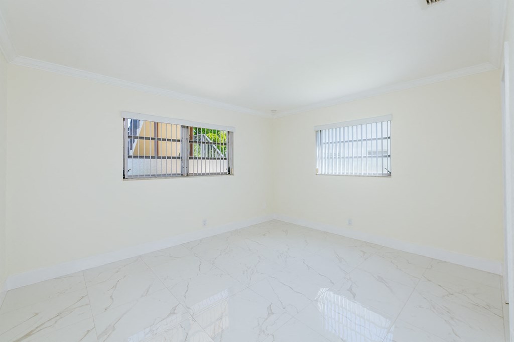 an empty room with two windows and a marble floor