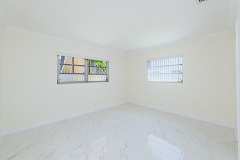 an empty room with two windows and a marble floor
