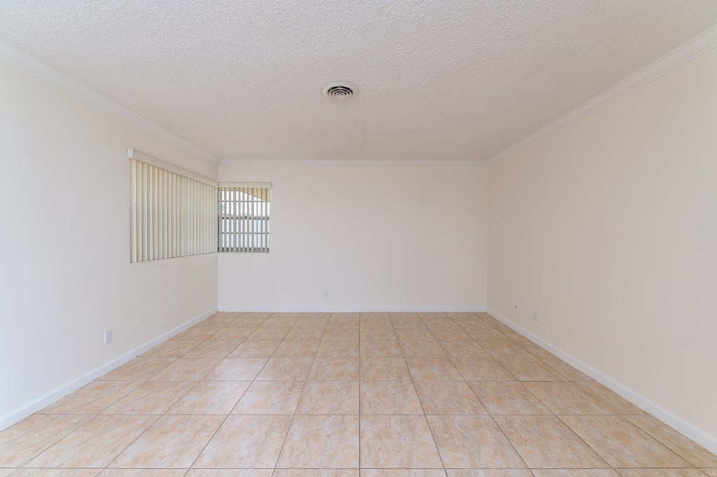 an empty living room with tiled floors and a window
