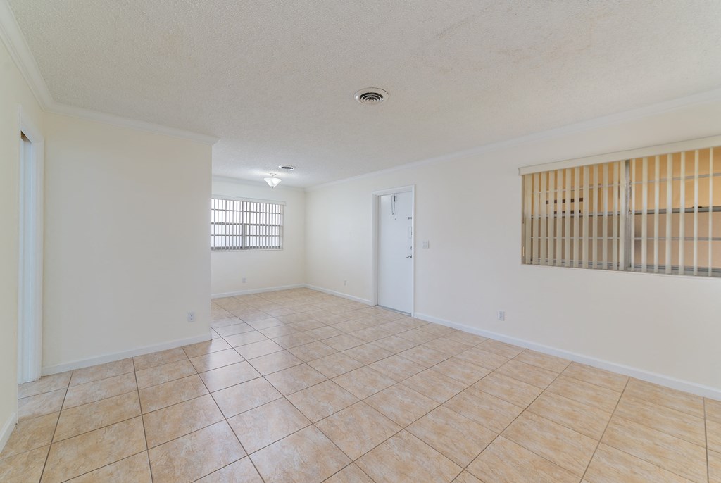 the spacious living room and dining room of an empty apartment