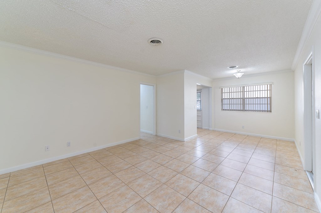 the living room and dining room of an empty home with tile flooring