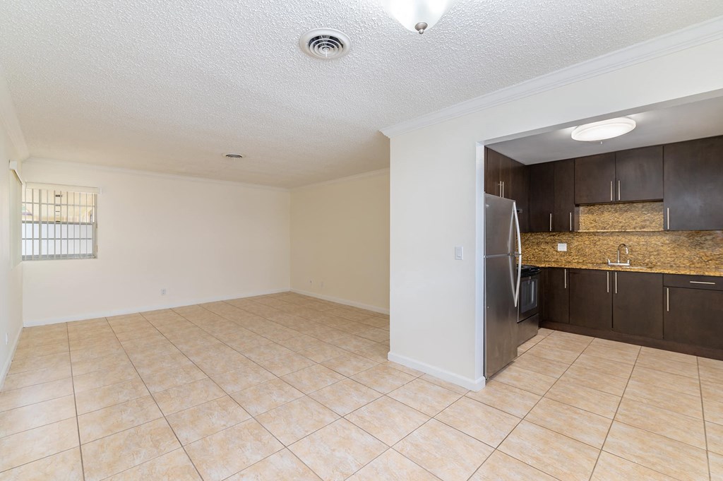 an empty kitchen and living room with a stainless steel refrigerator