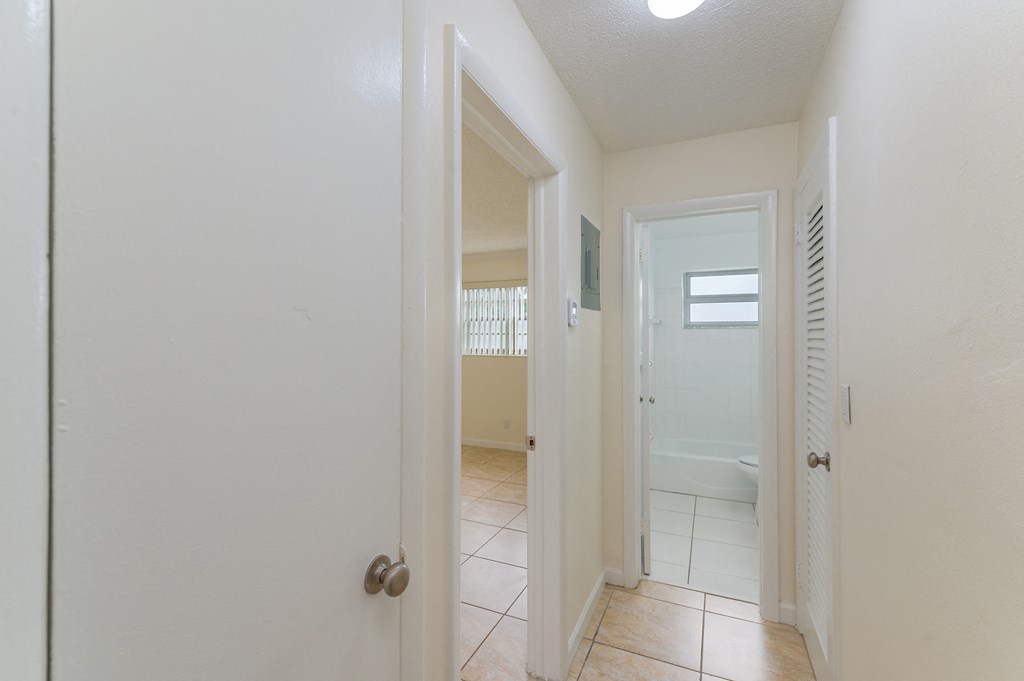 a hallway with a door open to a bathroom and a closet