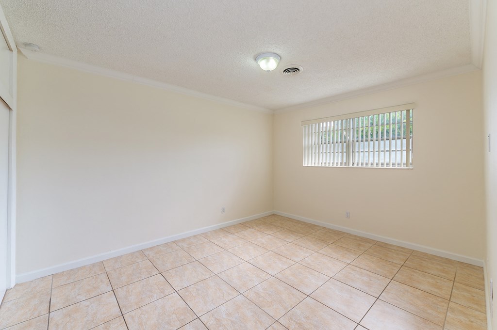 an empty living room with tile flooring and a window