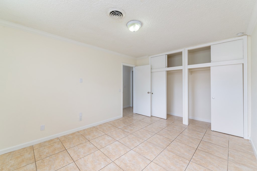 an empty living room with tile floor and white closet doors