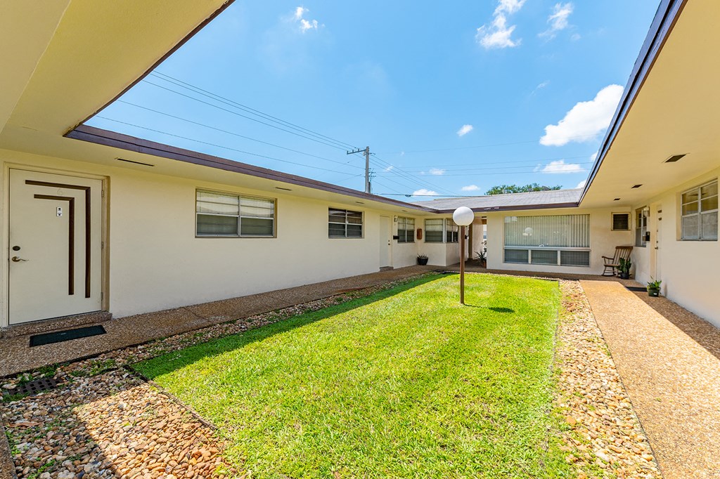 a courtyard with a grass lawn and a white house
