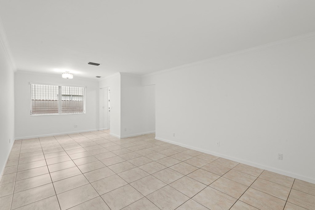 the living room and dining room of an empty home with tiled flooring