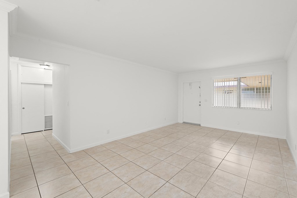 the living room and dining room of a house with white walls and tiled floors