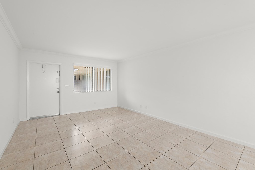 the living room and dining room of a house with tiled floors and white walls