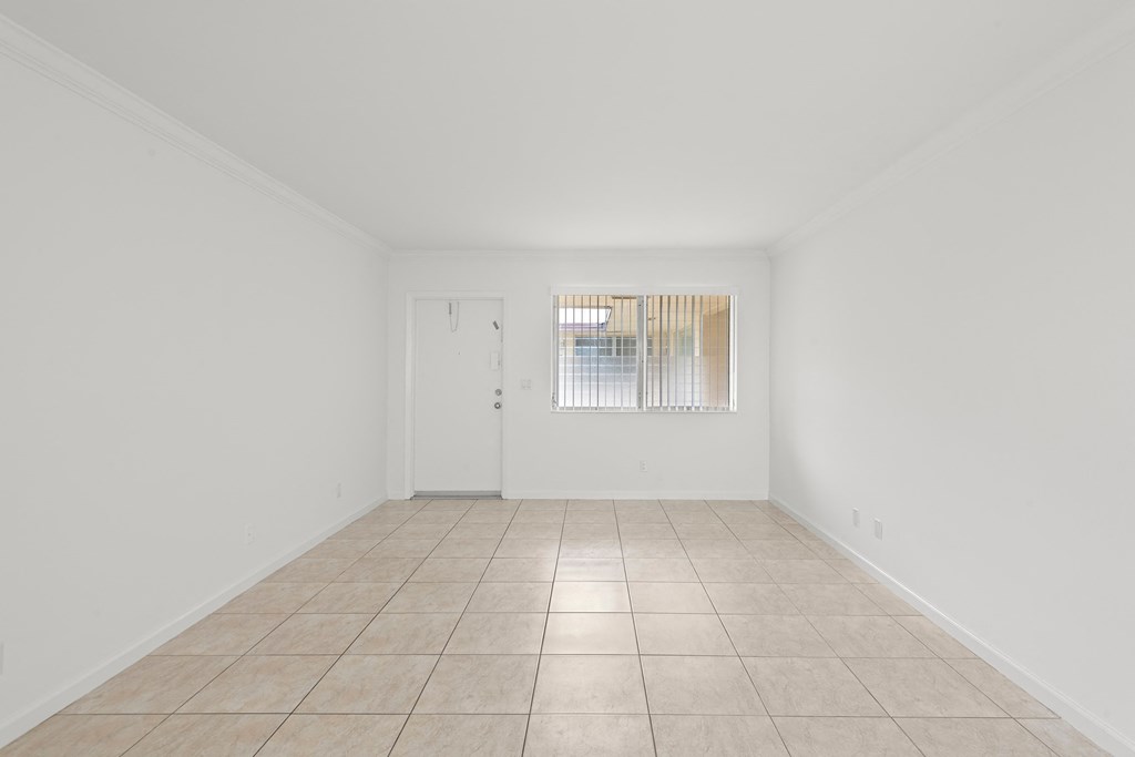 the living room of a house with white walls and a tiled floor