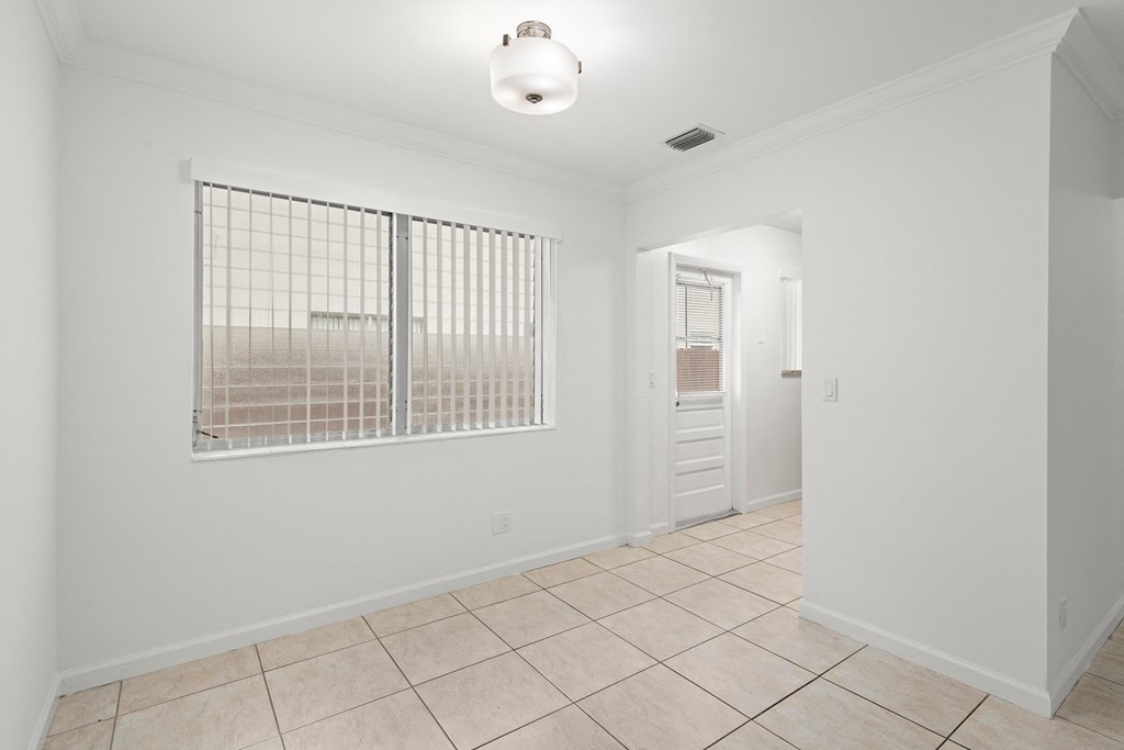 the living room and entryway of a house with white walls and tile flooring