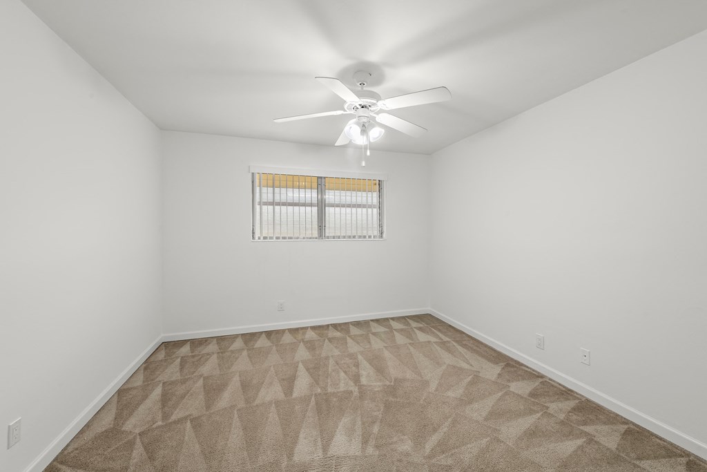 a spacious living room with white walls and a ceiling fan