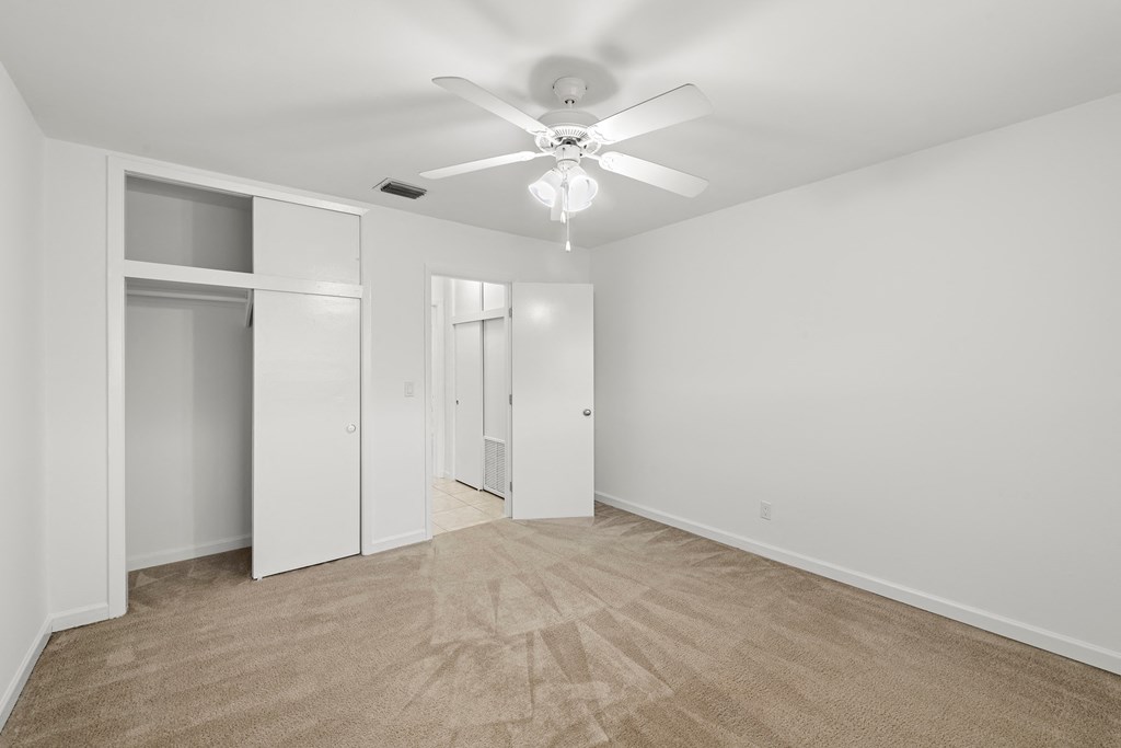 a living room with white walls and a ceiling fan