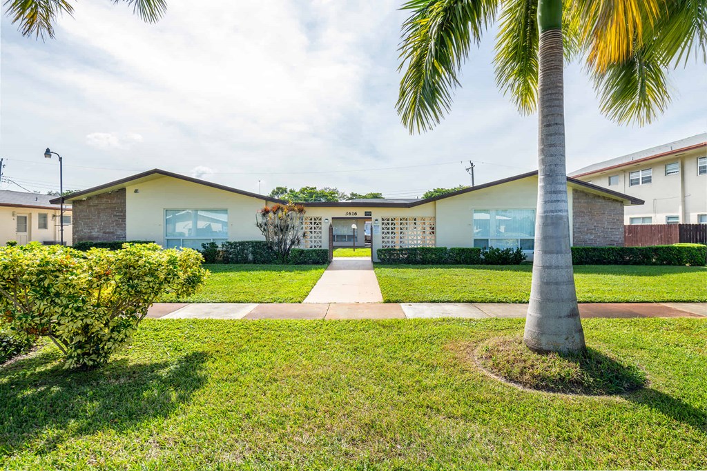 a house with a sidewalk and palm trees in front of it