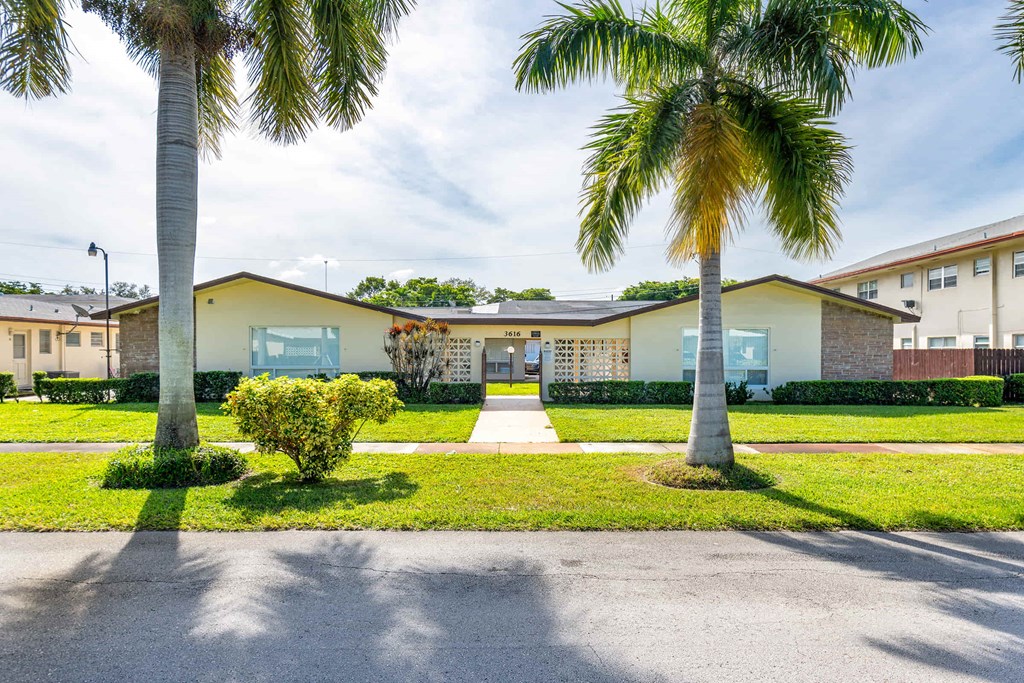 a house with palm trees and a sidewalk in front of it
