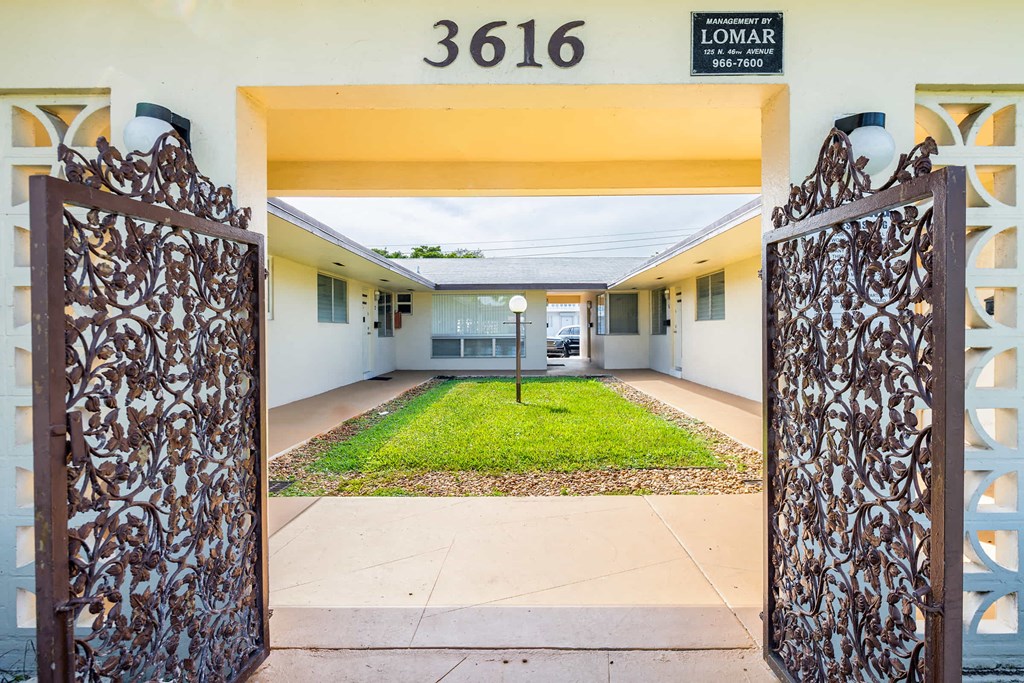 the entrance to a school with two gates and a lawn