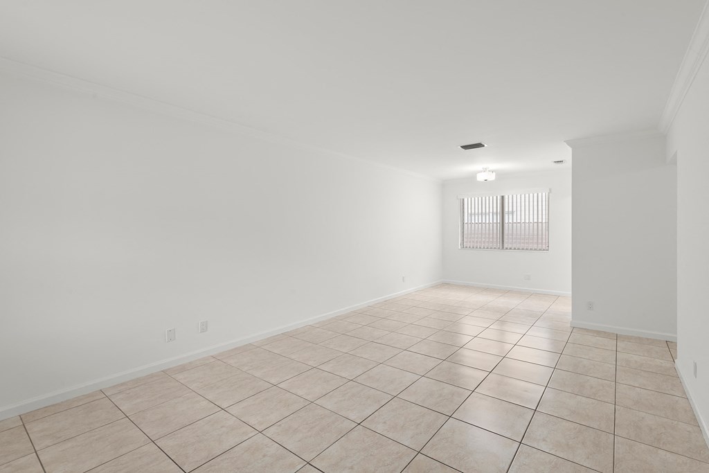 an empty living room with tiled floor and white walls