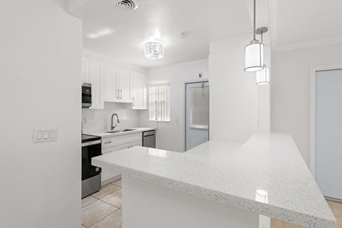 a renovated kitchen with white countertops and white cabinets and a large white counter top