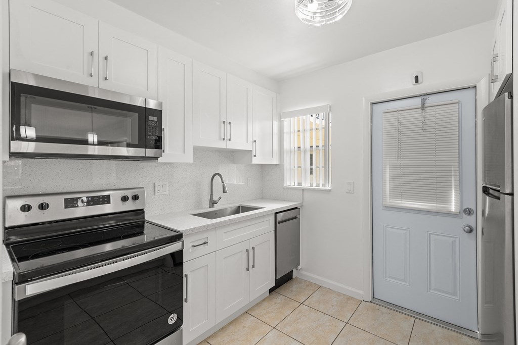 a kitchen with white cabinets and black appliances and a door