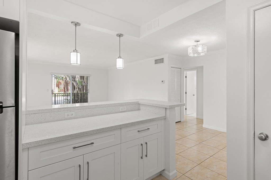 a white kitchen with white cabinets and a door to a hallway