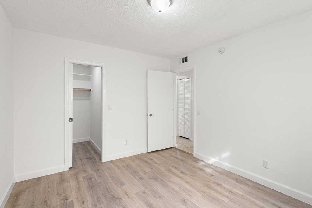 a spacious living room with white walls and wood flooring