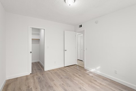a spacious living room with white walls and wood flooring