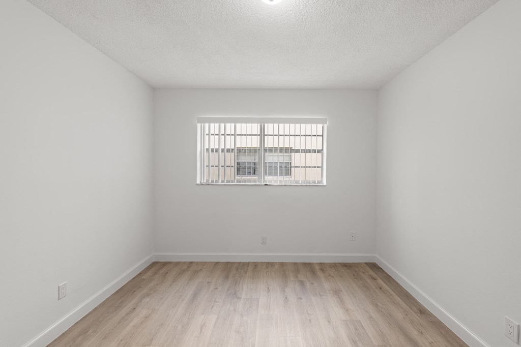 the living room of an apartment with wood flooring and a window