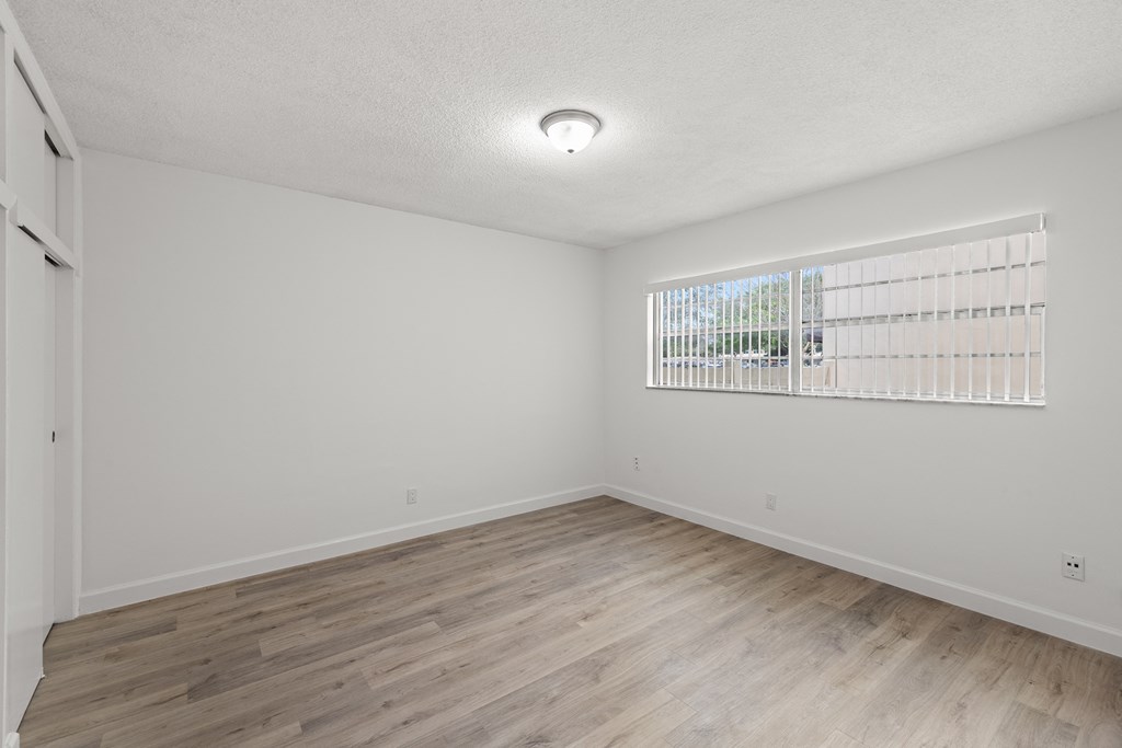 a spacious living room with wood flooring and a window