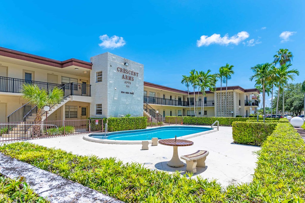 a swimming pool in front of a building with palm trees