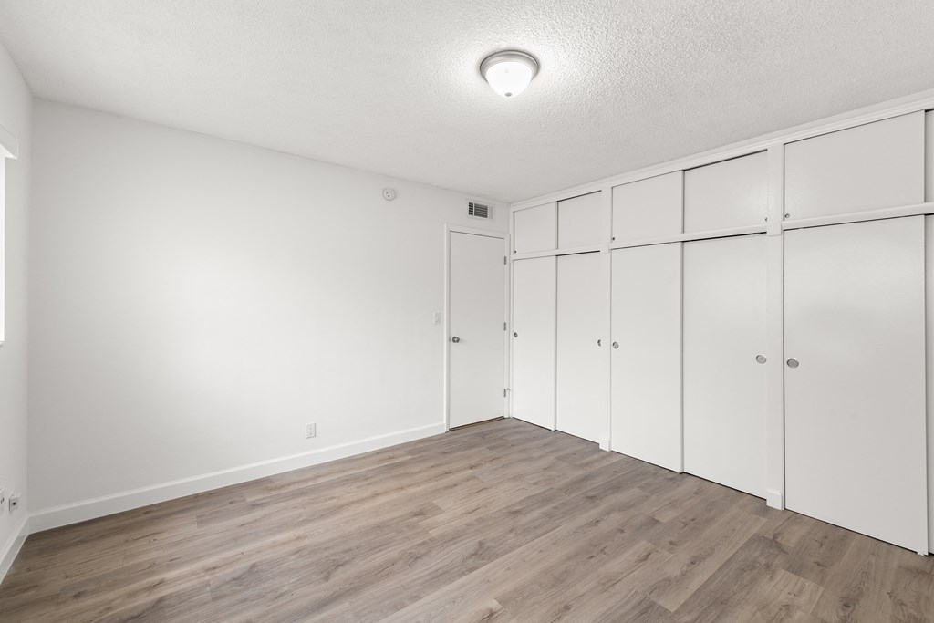 an empty room with white closets and wood flooring