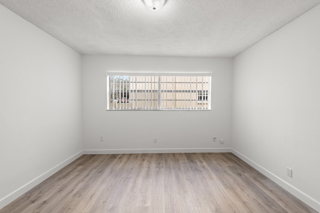a spacious living room with wood flooring and a window