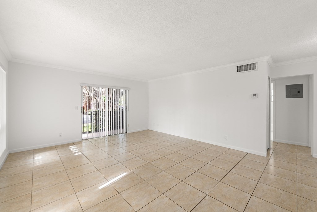 an empty living room with tiled floors and a sliding glass door