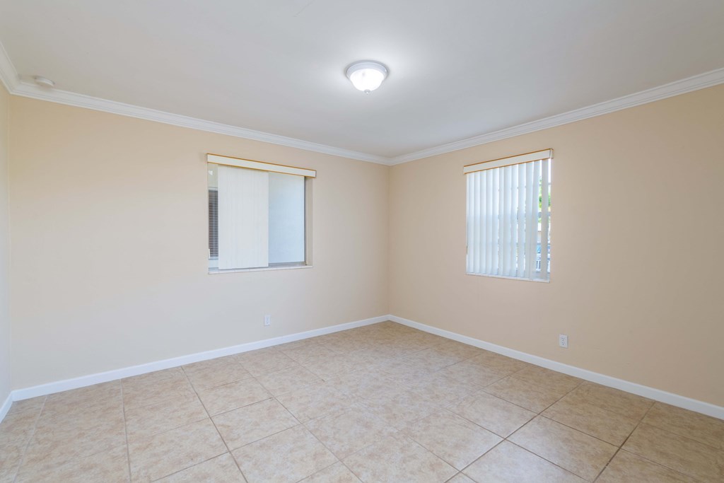 an empty living room with a window and a tiled floor