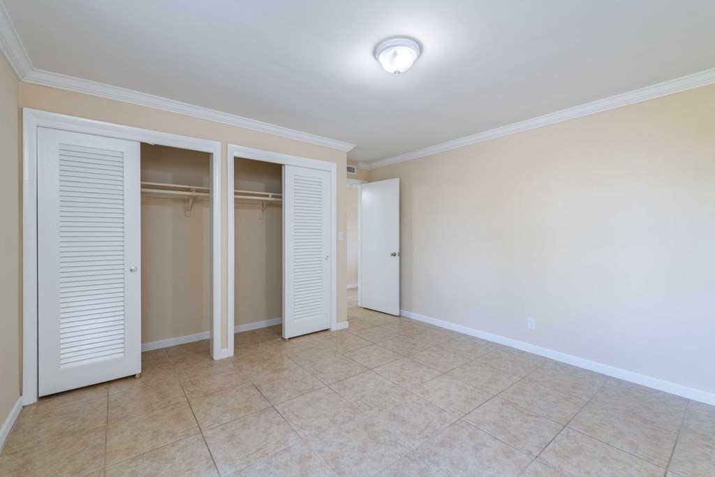 an empty living room with two closets and a tiled floor